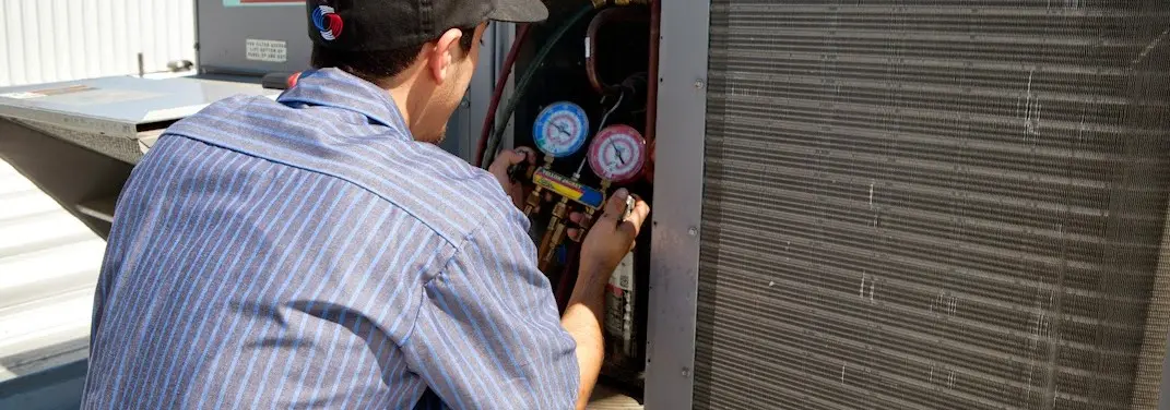 HVAC technician servicing a condenser unit in Palmdale